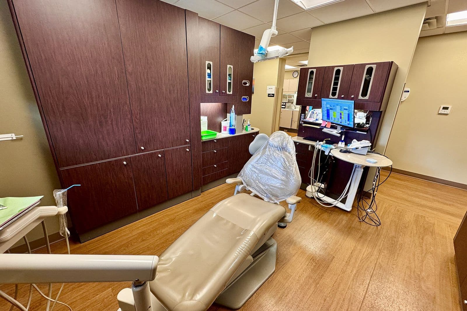 A dental treatment room with a chair, cabinets and a monitor, ready for the next patient